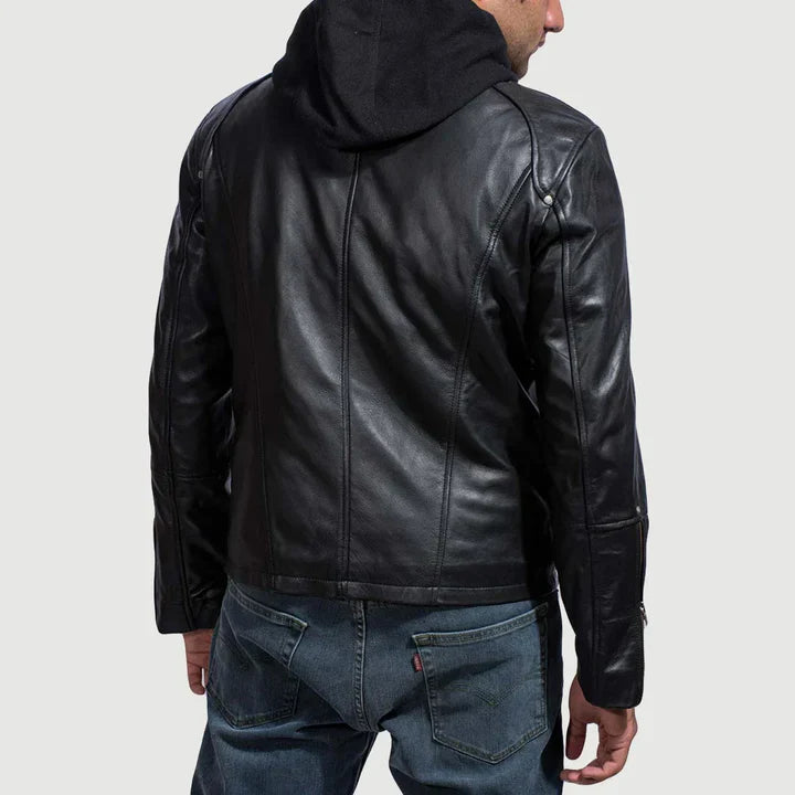 Person wearing a black leather jacket and blue jeans on a light gray background